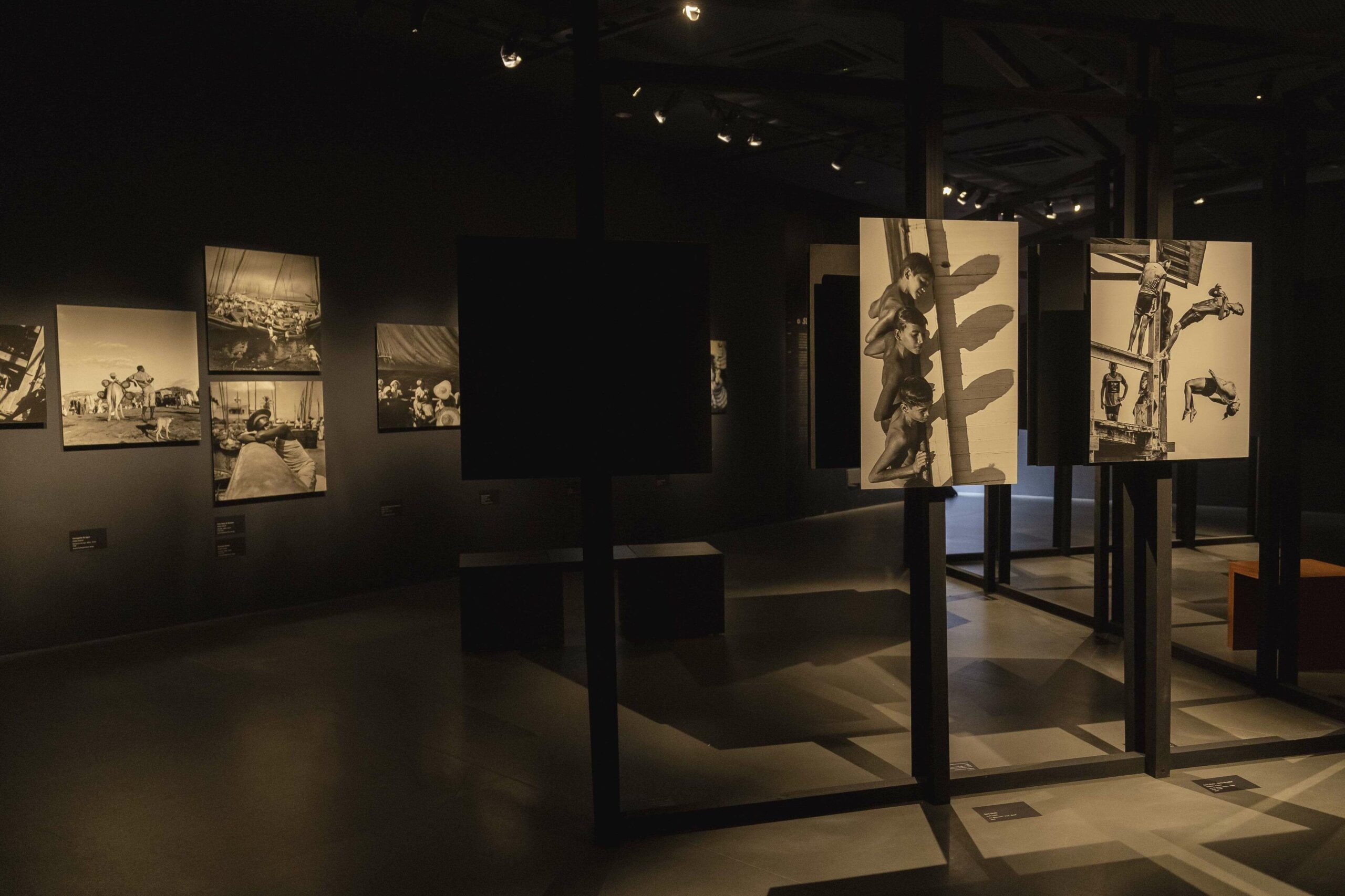 Sala escura com foco de luzes nos quadros, que são fotografias em preto e branco.