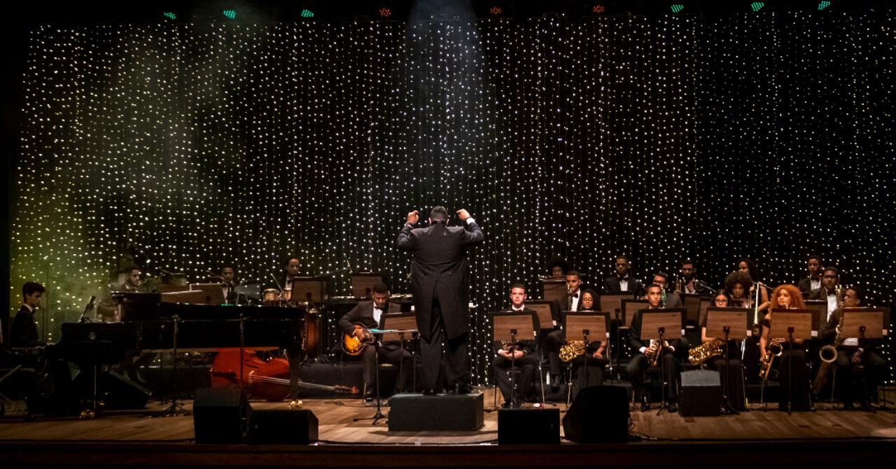 Foto de um maestro e músicos em um palco