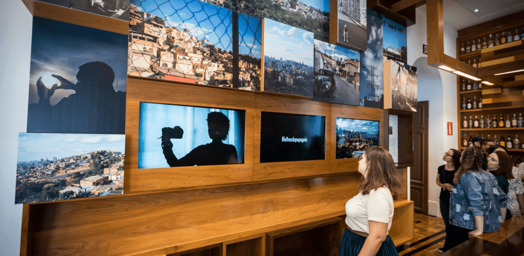 Pessoas em uma sala observam imagens de exposição.